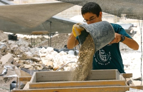 פרויקט סינון העפר מהר הבית נער שופך דלי של עפר למסננת